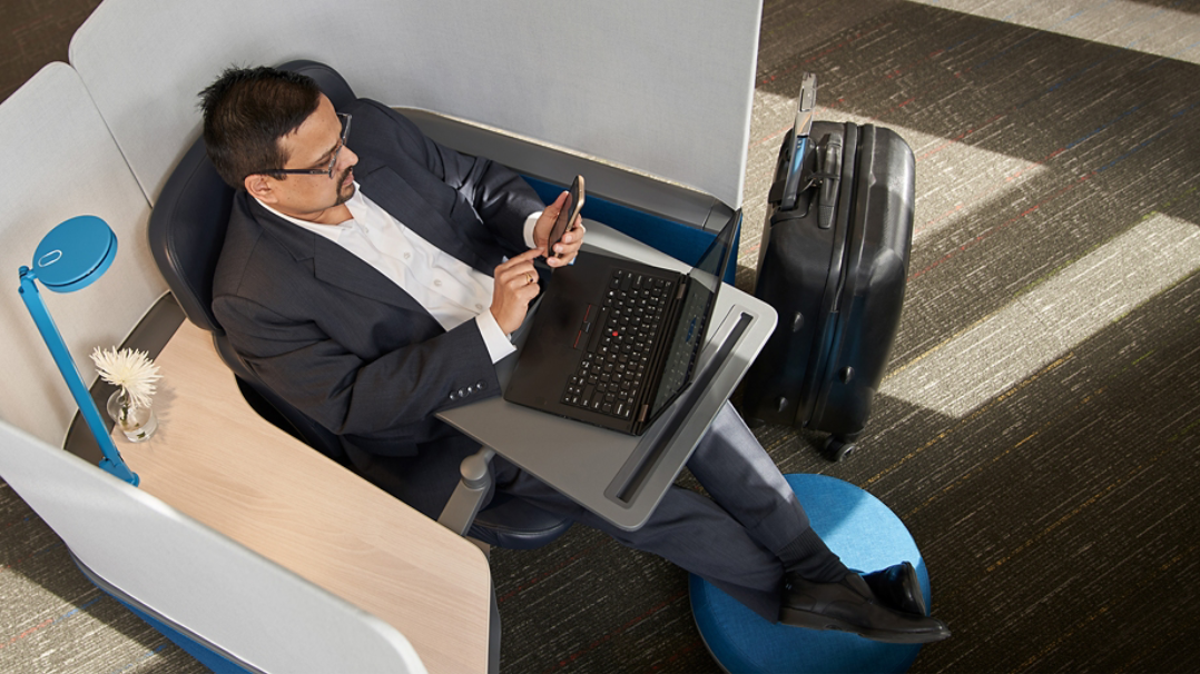 A man sitting in a chair while doing work on a laptop