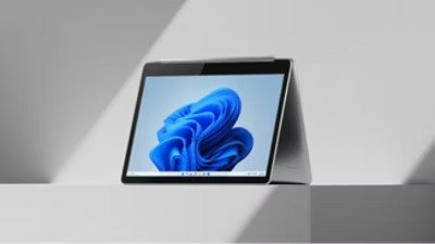 Microsoft device with the blue bloom on the screen sitting on a white table