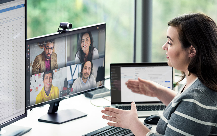 Female working at desk with multiple devices and running a Microsoft Teams conference call. 