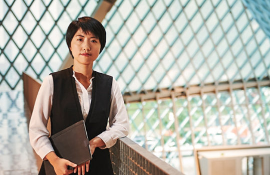 A professionally dressed woman standing in an office.