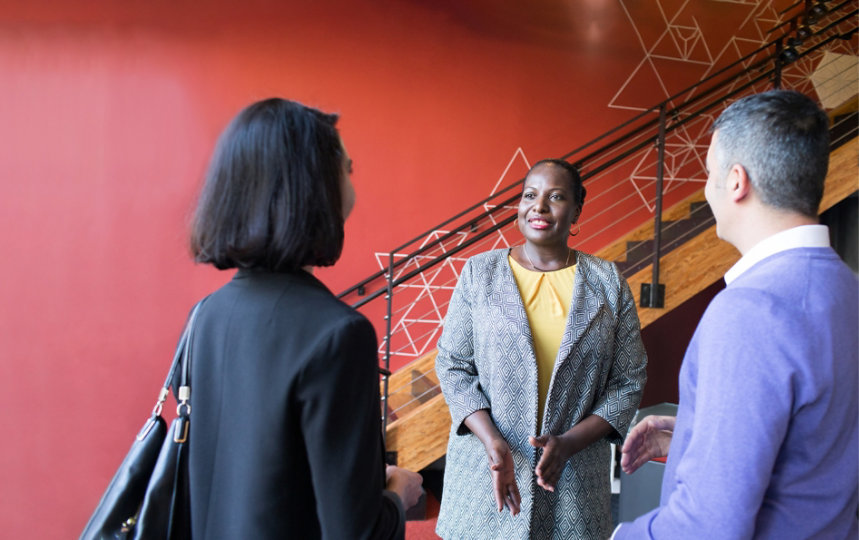 Three lawyers talking with each other in a foyer. 