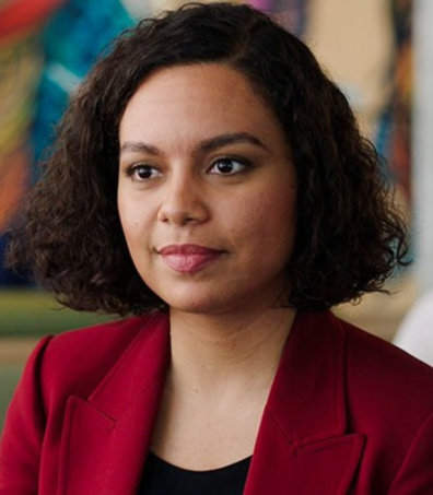 Nicole Walters from the SBC training video wearing a red blazer is looking off to the distance in thought.