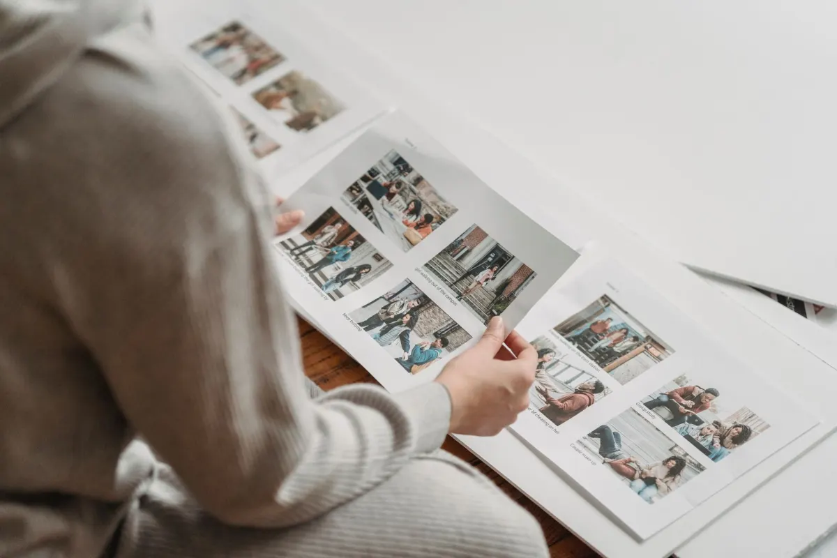 A photographer sorting printed contact sheets on a light table, matching the section on checking each carousel item against media specs before upload.