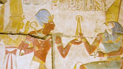 Ancient Egyptian carving of Pharaoh Seti I holding his flail before the god of the underworld Osiris with Horus behind him. Abydos Temple, Egypt. Ancient carving, on public display for 2,000 years