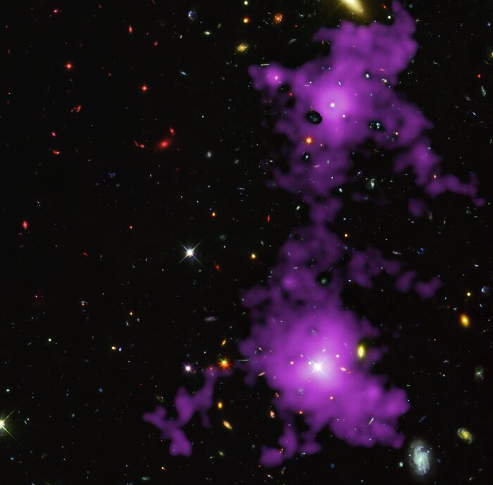 The image shows countless stars and galaxies in the background. Two galaxies are shown at the forefront, each with a bright nucleus, which indicates the presence of a quasar. The galaxies appear like large nebulae, without a concrete shape. The content of the galaxies extend beyond their immediate shape, forming a bridge that connects the two galaxies. This bridge is a cosmic filament.