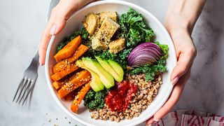 Baked vegetables, avocado, tofu and buckwheat buddha bowl.