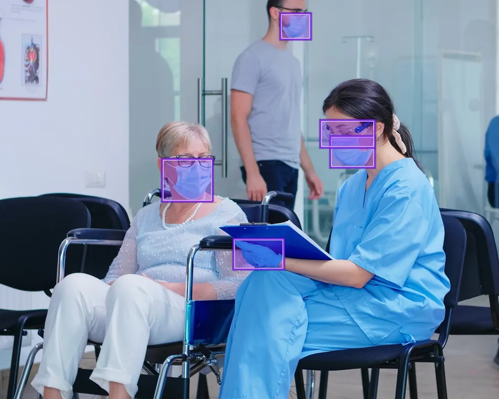 People wearing PPE in healthcare waiting room, with bounding boxes around masks and gloves