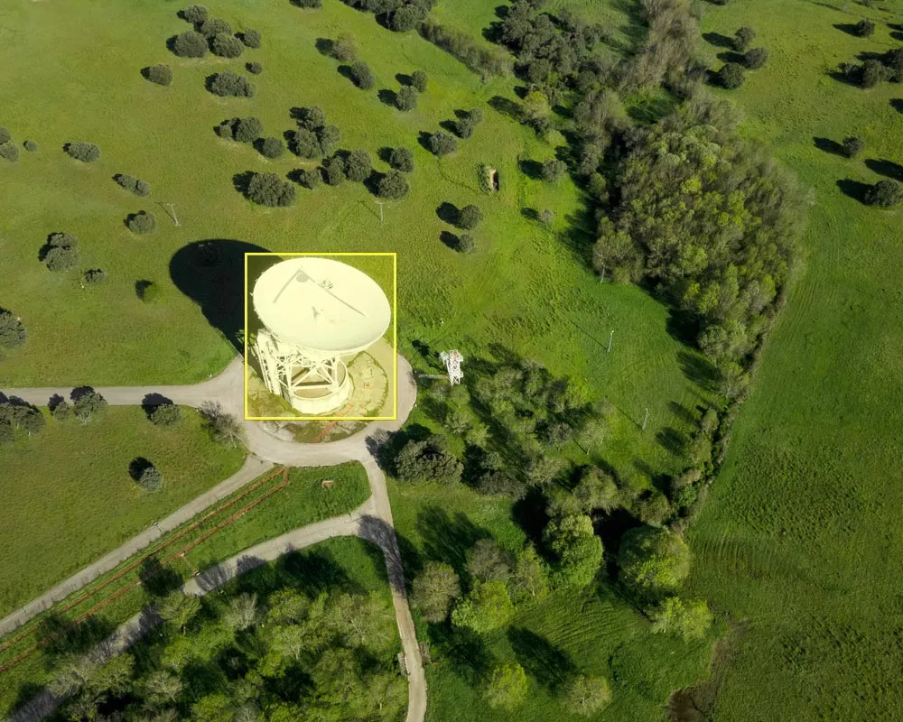 Aerial view of a large satellite dish in a field, with a bounding box drawn around it.