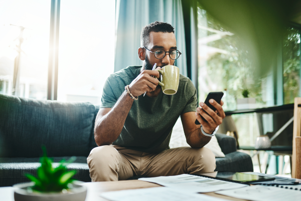 Man drinking coffee looking at mobile