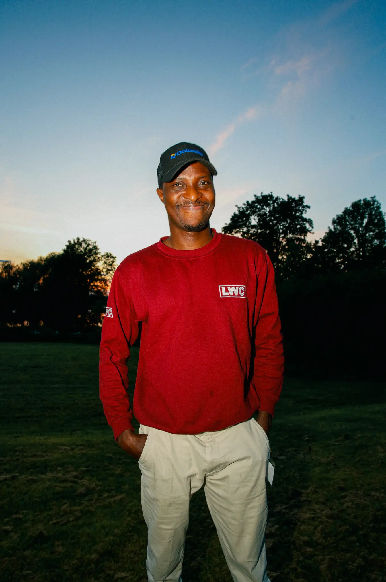 Image of a smiling man with a red crewneck sweaters.