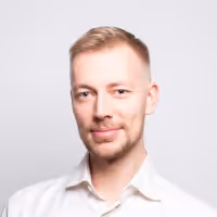 Portrait of a blond man with short hair and a white shirt against a white background.