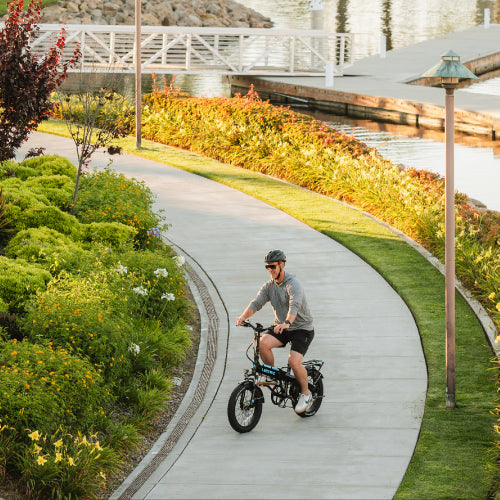 man riding lectric ebike on trail along water