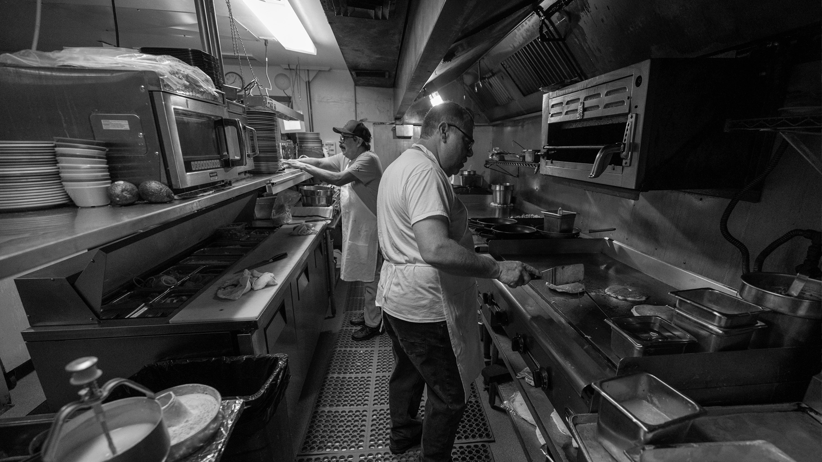 Two restaurant workers in a restaurant kitchen.