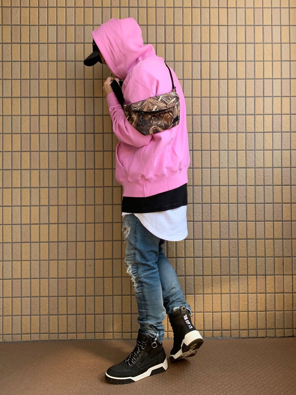 ピンク系のパーカー、ブルー系のデニムパンツ、ホワイト系のスニーカーを着用したメンズの春コーディネートの1枚目の写真