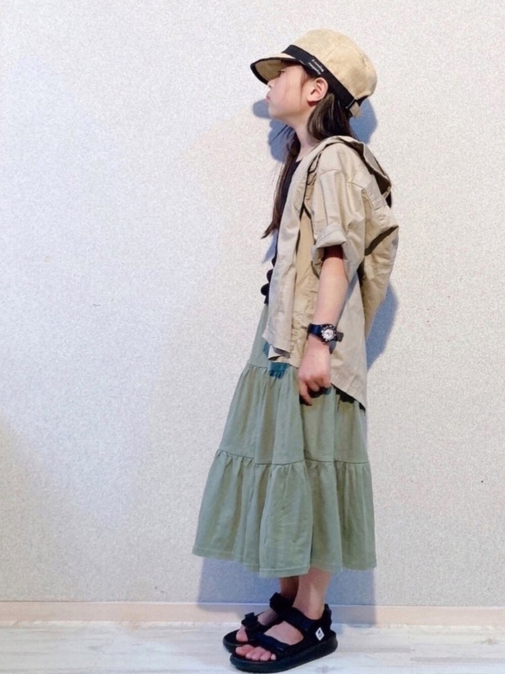 ブラック系のTシャツ/カットソー、ベージュ系のシャツ/ブラウス、グリーン系のスカートを着用したキッズの春コーディネートの1枚目の写真
