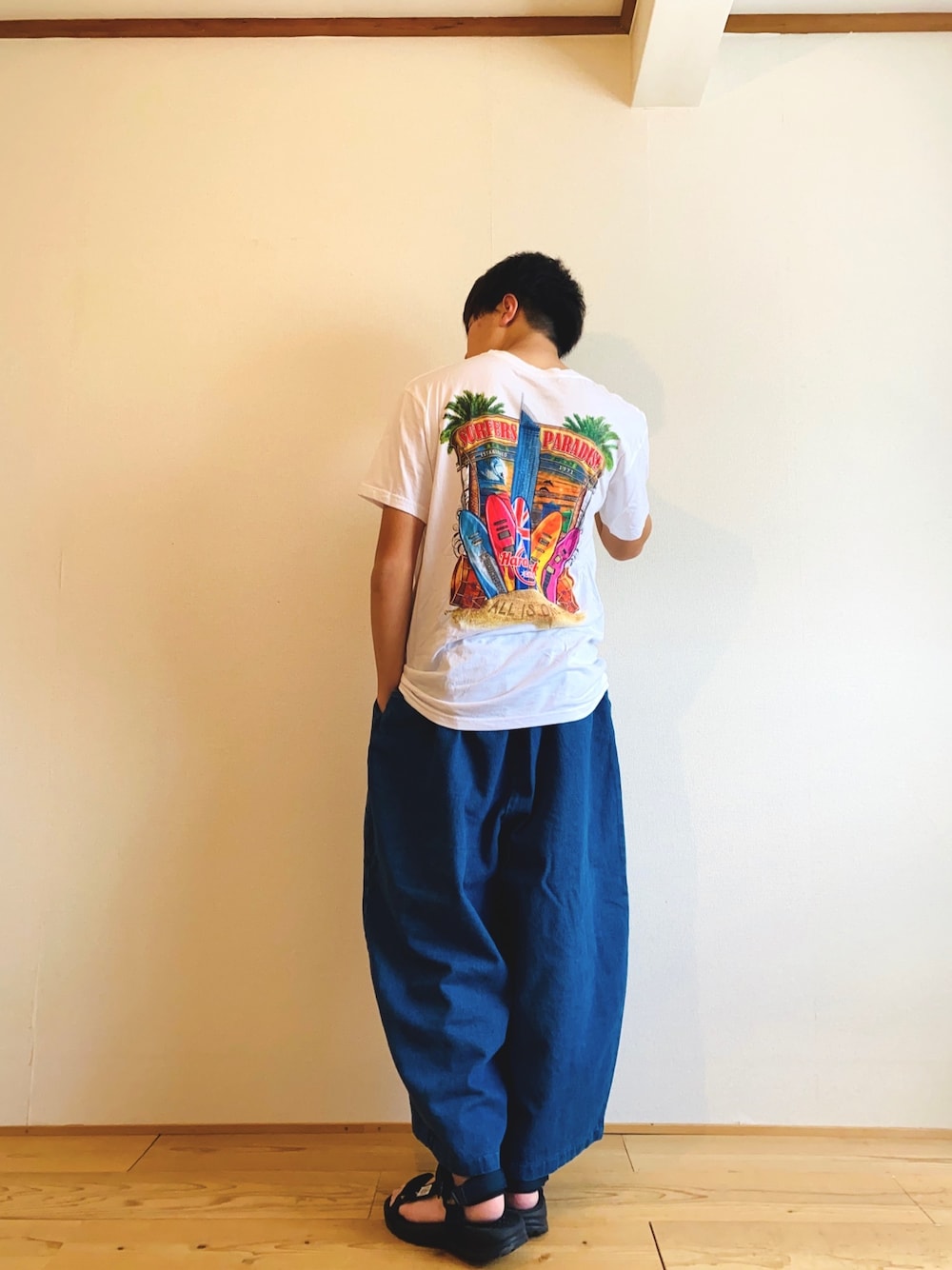 ブルー系のデニムパンツ、ホワイト系のトップス、ブルー系のサンダルを着用したメンズの夏コーディネートの1枚目の写真