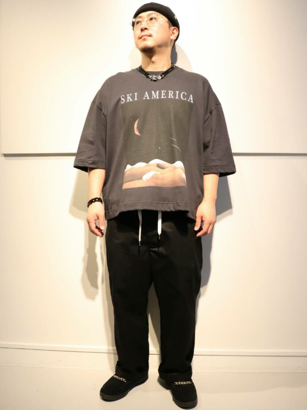 ブラック系のTシャツ/カットソー、ブラック系のニットキャップ/ビーニー、グリーン系のサングラスを着用したメンズの春コーディネートの1枚目の写真