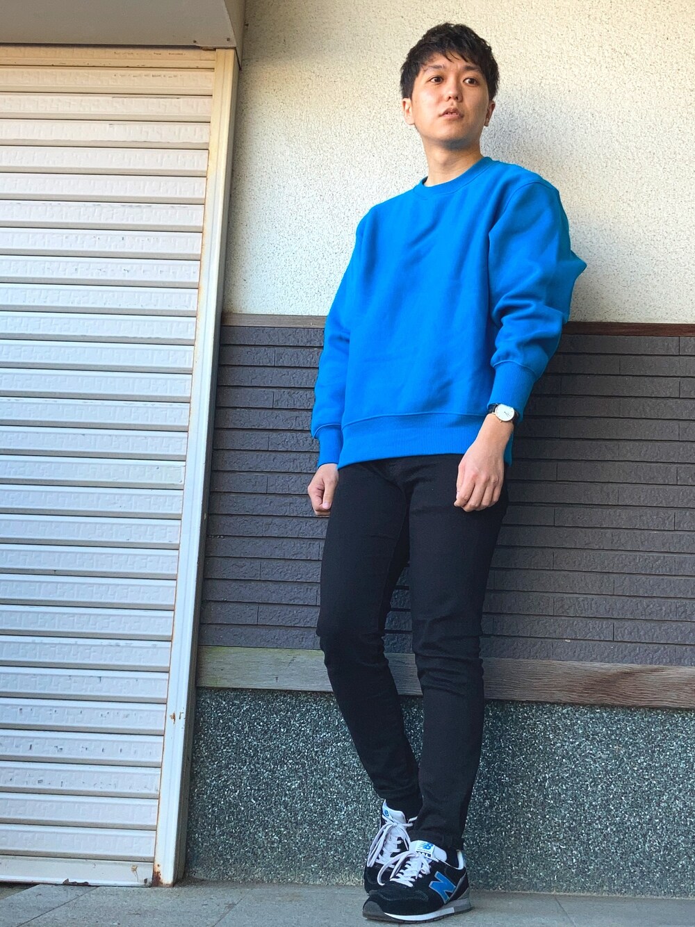 ブルー系のスウェット、ブラック系のデニムパンツ、ブラック系のスニーカーを着用したメンズの秋コーディネートの1枚目の写真