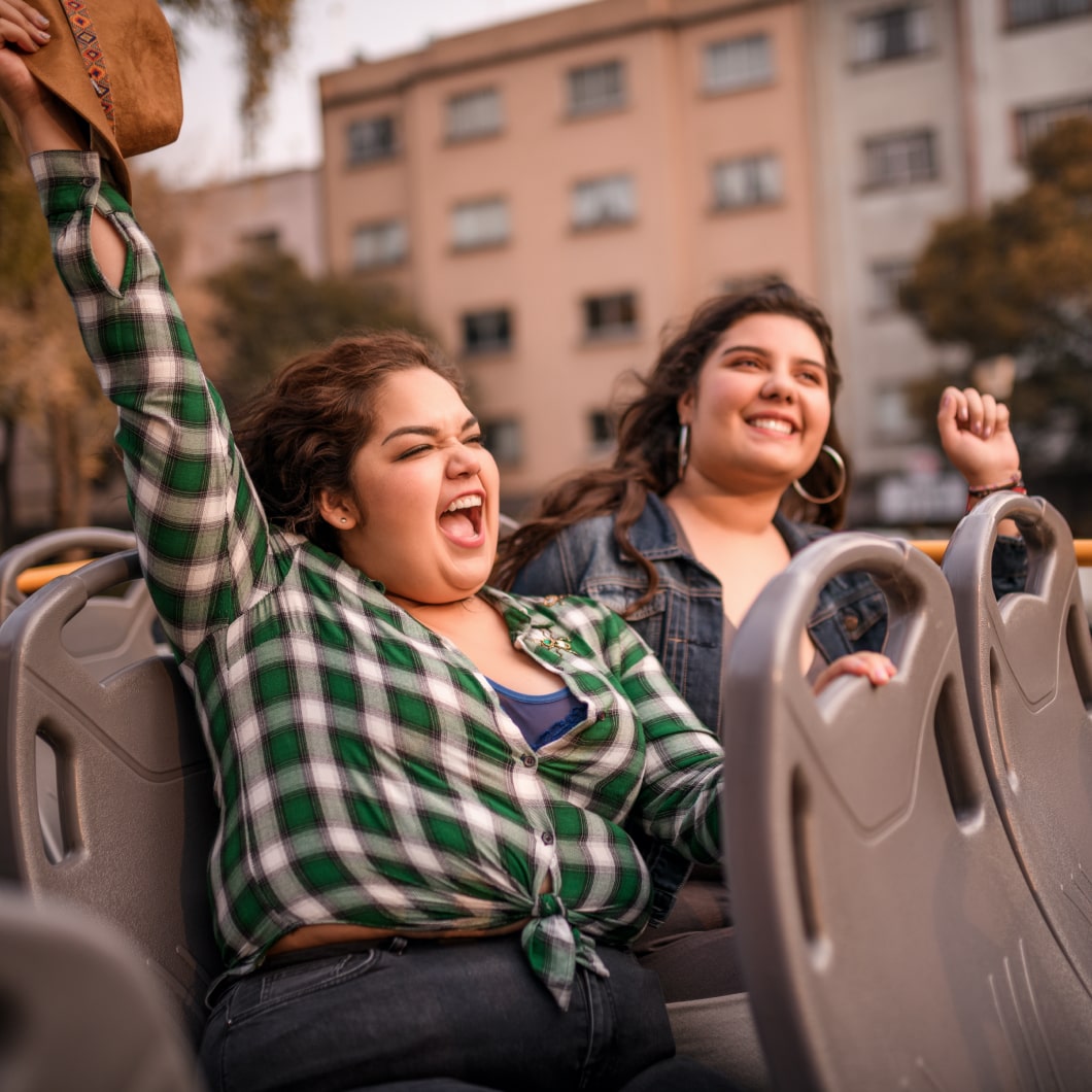 Dos viajeras felices en la parte de arriba de un micro de dos pisos