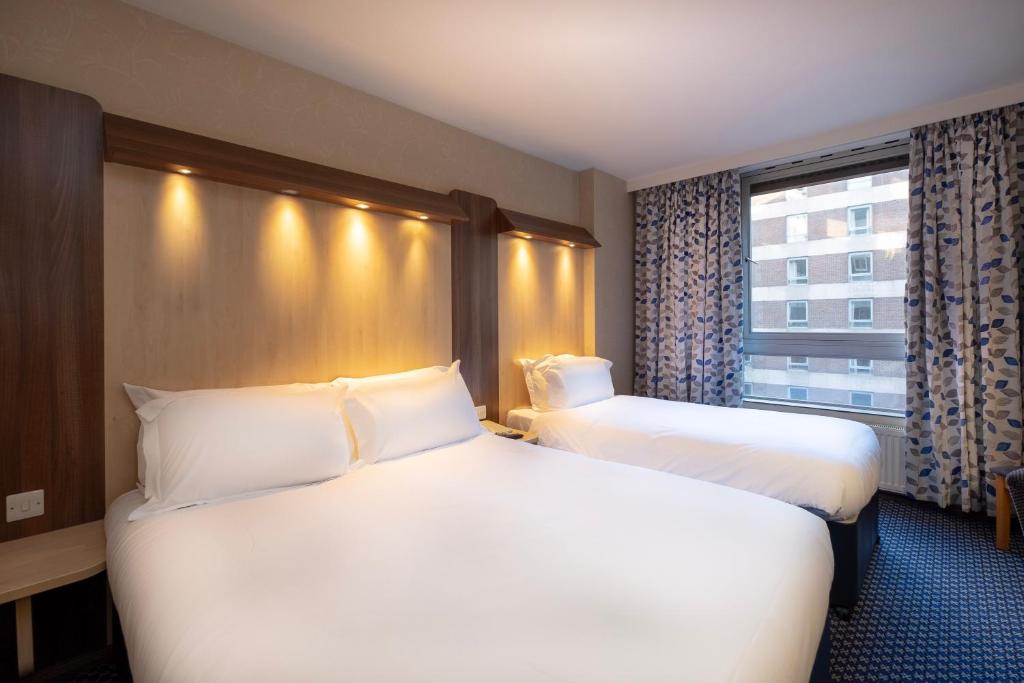 a hotel room with two beds and a window at Royal National Hotel in London