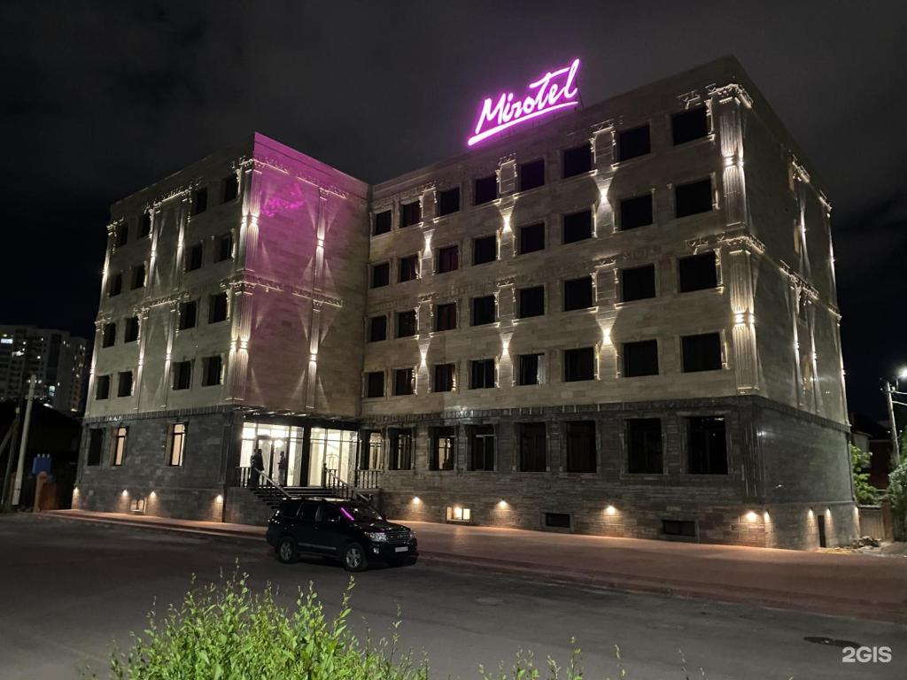 a building with a neon sign on top of it at MirOtel Hotel in Astana