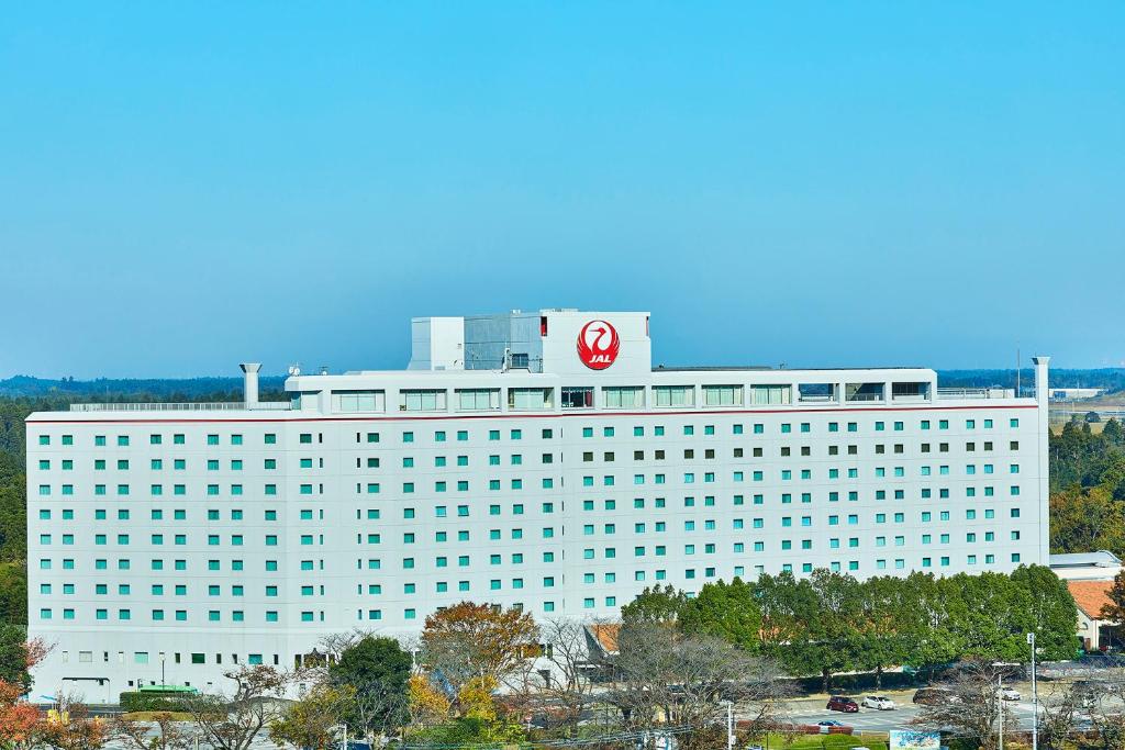 un grande edificio bianco con un cartello rosso di Hotel Nikko Narita a Narita