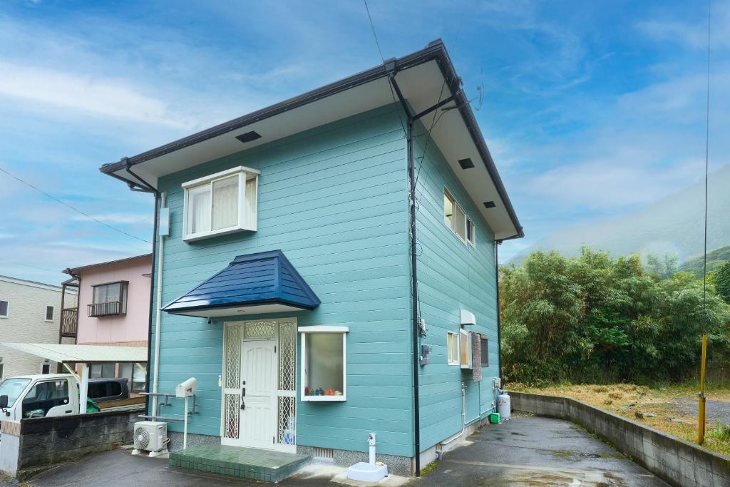 ein blaues Haus mit schwarzem Dach in der Unterkunft 堀田フォレストハウス in Beppu