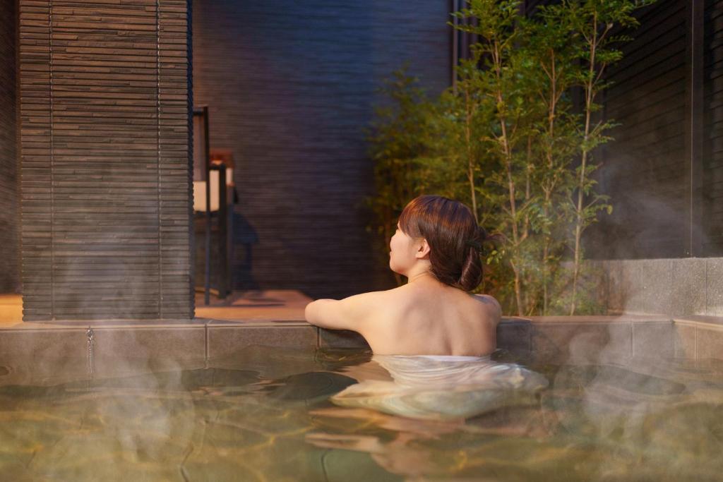 een vrouw in een bad in een hot tub bij 三和泉 in Beppu