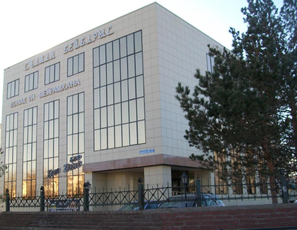 a large white building with a tree in front of it at Sultan Beibarys in Astana