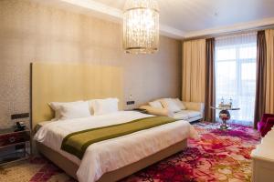 a bedroom with a large bed and a chandelier at The ONE Hotel Astana in Astana