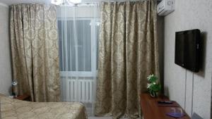 a bedroom with a window with curtains and a television at Hotel Shagyn in Astana