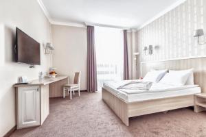 a bedroom with a bed and a desk and a television at AYKUN Hotel by AG Hotels Group in Astana