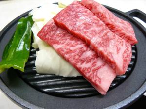 two pieces of meat and cheese on a black plate at Ryokan Yamashiroya in Yufuin