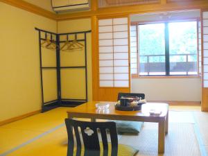 a room with a table and two chairs and a window at Ryokan Yamashiroya in Yufuin