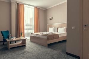 a bedroom with a bed and a desk and a window at AYKUN Hotel by AG Hotels Group in Astana