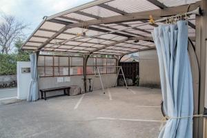 a covered patio with blue curtains and a bench at Guest House Asora in Aso