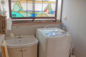 a bathroom with a washing machine and a stained glass window at Guest House Asora in Aso