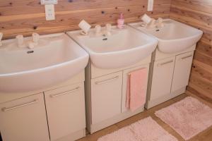 two sinks in a bathroom with white cabinets at Guest House Asora in Aso