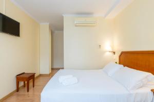 una camera con letto bianco e TV a schermo piatto di Hotel Residencial Colibri a Costa da Caparica