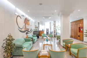 una sala d'attesa con sedie verdi e tavolo di Hotel Residencial Colibri a Costa da Caparica