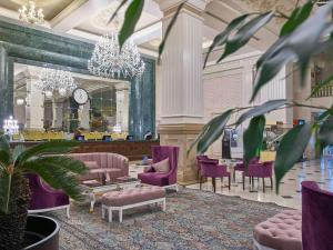 a lobby with purple chairs and a table and a clock at Rixos President Hotel Astana in Astana