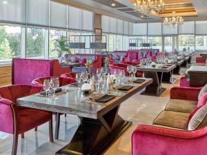 a row of tables in a restaurant with purple chairs at Rixos President Hotel Astana in Astana