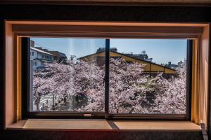 uma janela com vista para uma árvore com flores cor-de-rosa em Hotel Alza Kyoto em Quioto