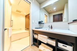 ein Badezimmer mit einem Waschbecken, einer Badewanne und einem Spiegel in der Unterkunft Rakuten STAY Kokura Station Family Room in Kitakyūshū