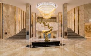 a lobby with a large chandelier and a statue of a tree at Hilton Astana in Astana