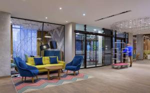 a lobby with a yellow couch and blue chairs at Hampton By Hilton Astana Triumphal Arch in Astana