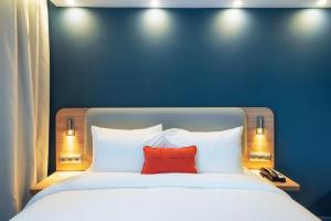 a bed with a red pillow in a blue wall at Holiday Inn Express - Astana - Turan by IHG in Astana