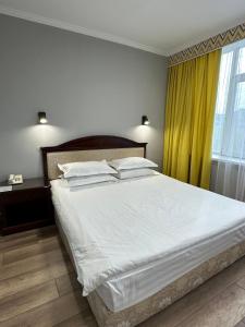 a bedroom with a large white bed with yellow curtains at G Empire in Astana