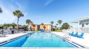 a swimming pool with blue chairs and palm trees at Emerald Escape Peekaboo Beach View 3 Pools in Destin