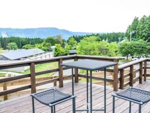 een tafel en twee stoelen op een houten terras bij Kosugi Resort in Aso